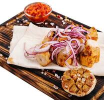 Chicken fillet skewers on tortilla served with red onion photo