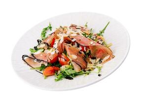 Salad with prosciutto, tomato, arugula leaves on plate photo