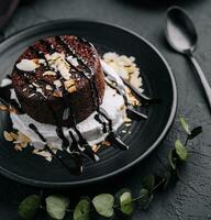 Plate with fresh brownies and ice-cream on black plate photo