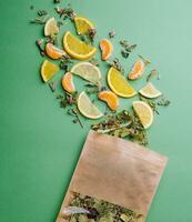 Leaf tea spilled out of a paper packet with orange and tangerine slices photo