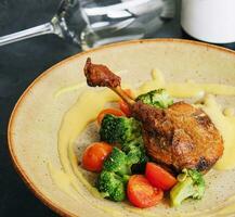 Confit duck leg with broccoli and tomatoes photo