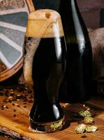vaso de oscuro cerveza y botella en de madera foto