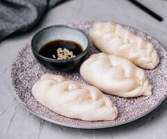 uncooked asian dumplings with soy sauce photo