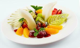 Fresh fruit salad on white plate isolated on white photo