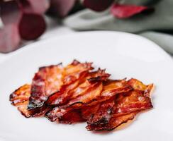 Plate with tasty bacon slices on stone photo