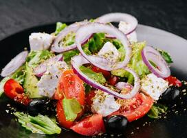 Greek salad in black bowl on stone photo