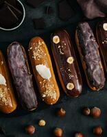 Sweet chocolate eclairs on black wooden board photo