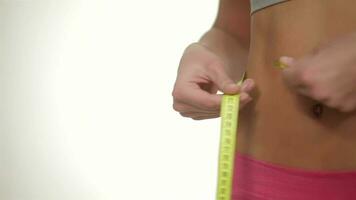 Athletic female measuring waist, isolated over white background video