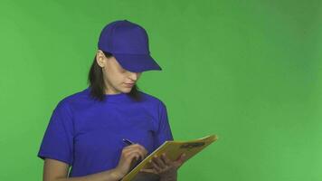 Young delivery woman checking papers on a clipboard smiling to the camera video