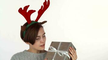 Happy woman in reindeer antlers headband looking at her Christmas present video