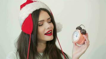 mooi meisje in de kerstman hoed poseren met klok video