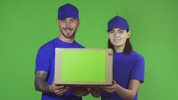 Two happy professional delivery workers holding out package box to the camera video