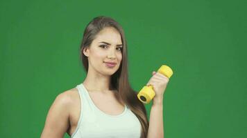 Happy beautiful sportswoman holding dumbbell and a bottle of water smiling video