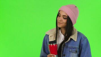 Gorgeous young woman wearing warm hat and jacket having tea video