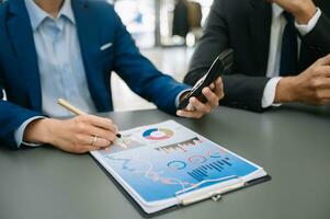 Business documents on office table with smart phone and calculator digital tablet and graph business with social network diagram and two colleagues discussing data working in the modern office photo
