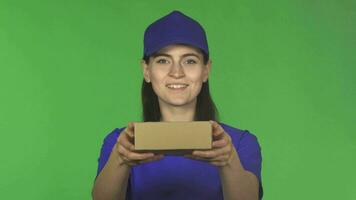 Happy delivery woman smiling holding out small package to the camera video