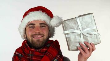 Handsome bearded man in Christmas hat smiling, holding up a present video