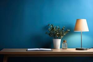 Table with lamp, plant and handles against a blue wall. Workplace, minimalism. photo