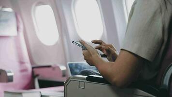 in viaggio e tecnologia. volante a primo classe. bella giovane imprenditori donna utilizzando smartphone mentre seduta nel aereo. video