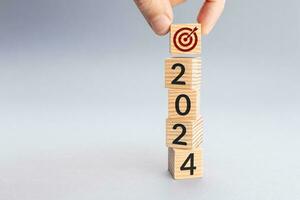 Hand holding a target icon on top of Wooden blocks with 2024 number. 2024 business goal concept. Copy space photo