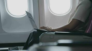 Woman using laptop while is sitting in plane near window. video