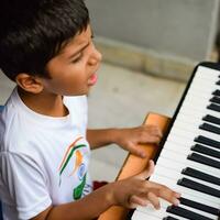 asiático chico jugando el sintetizador o piano. linda pequeño niño aprendizaje cómo a jugar piano. niño manos en el teclado interior. foto