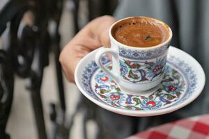 hand holding a a cup of turkish coffee on table photo