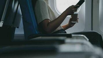 portrait of A successful asian business woman or female entrepreneur in formal suit in a plane sits in a business class seat and drink coffee during flight, relax concept video