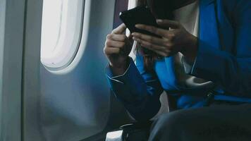 op reis en technologie. vliegend Bij eerste klas. mooi jong zakenmensen vrouw gebruik makend van smartphone terwijl zittend in vliegtuig. video