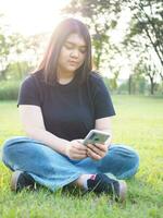 portrait young woman asian chubby cute beautiful one person wear black shirt look hand holding using smart phone in garden park outdoor evening sunlight fresh smiling cheerful happy relax summer day photo