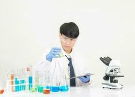 Portrait Asian man student scientist Wearing a doctor gown in the lab looking hand at chemist. caused by mixing reagents in scientific research laboratories with test tubes and microscope on the table photo