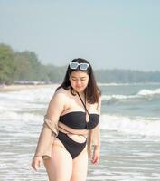 Portrait young woman asian chubby fat cute beautiful one person in bikini black sexy frontview tropical sea beach white sand clean and blue sky background calm nature ocean wave water travel fun happy photo