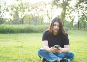 portrait young woman asian chubby cute beautiful one person wear black shirt look hand holding using smart phone in garden park outdoor evening sunlight fresh smiling cheerful happy relax summer day photo