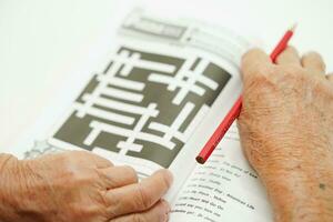 asiático mayor mujer jugando sudoku rompecabezas juego para tratamiento demencia prevención y Alzheimer enfermedad. foto