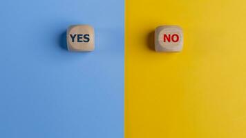 Wooden cube with yes and no text on a blue and yellow background. Business Choices For Difficult Situations, making Decisions. photo