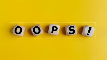 The wooden cubes with the word oops on a yellow background. Apologies for any mistake or error photo