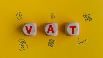 Vat business concept text on wooden cubes and icon on a yellow background. photo