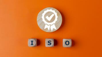 ISO quality control certification concept, top view of wooden blocks with word ISO and certificate sign. on an orange background. photo