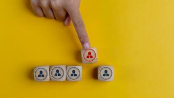 Hand choose wooden cubes with employee icons. Leadership, manager assignment, organizational hierarchy in business concept. photo