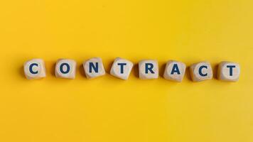 Wooden cubes with the word CONTRACT are written. Business concept. on a yellow background photo