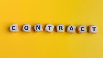 Wooden cubes with the word CONTRACT are written. Business concept. on a yellow background photo