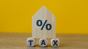 Property tax concept. investment planning.Wooden blocks with the word TAXES and a house on a yellow background. photo