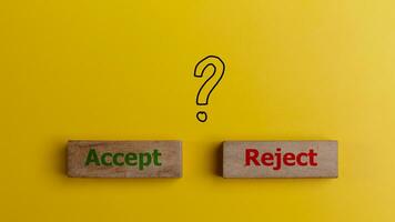The words accept and reject on wooden blocks with question mark symbols. Dilemma or choice between to approve or to refuse an application concept. photo