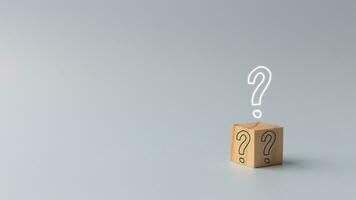 question mark on a wooden cube over a grey background.  FAQ concept, ask questions, find answers online in customer support. photo