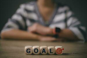 Goals word on a wooden cube with a target icon woman using the smartwatch in the background. GOAL Business concept. photo