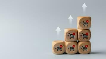 Wooden cubes with shopping cart icons and increasing trend-up graph. Increase higher sale volume and shopping trolley cart for online e-commerce business and internet marketing strategy concept. photo