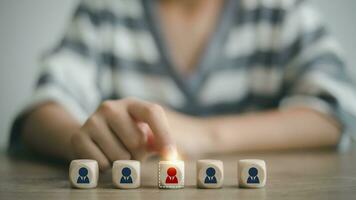 The woman picks a red human icon on the wooden cube. Customer rating employees by service experience, Human Resources management chooses a leader for the team resources management and recruitment. photo