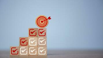 Check mark and dartboard from top of wooden cube stacks. Keys for success in business. Checklist, Complete Task list. Goals achievement or enterprise objective target for company success. To do list. photo