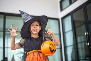 Happy Asian child girl in a witch costume to Halloween. trick or treat. Kids trick or treating. photo