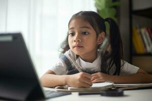 Young Asian Cute girl studying with laptop at home. Online learning concept. photo